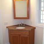 small bathroom corner vanity interior. round white wash basin in brown wooden bathroom vanity on BHHNROZ