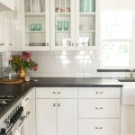 white kitchen cabinets, black countertops and white subway tile with white OBYDIPJ