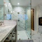 This beautiful marbled bathroom adds luxury with a mounted fireplace right  in the bathroom itself!