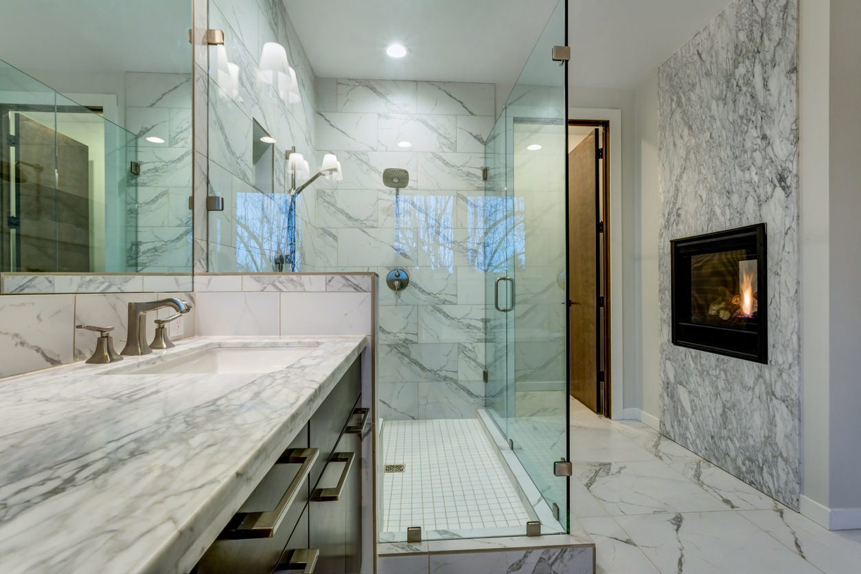 This beautiful marbled bathroom adds luxury with a mounted fireplace right  in the bathroom itself!