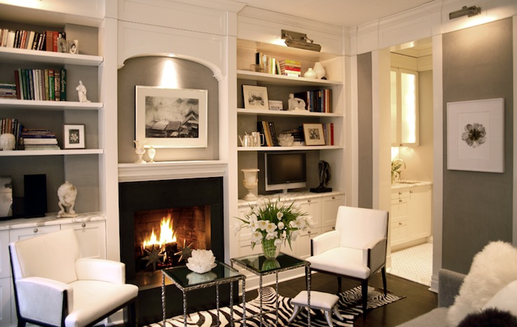 Gorgeous built-in bookshelves surrounding fireplace with sconce lighting.