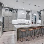 Contemporary kitchen with light gray cabinets, light wood floors and white  textured backsplash