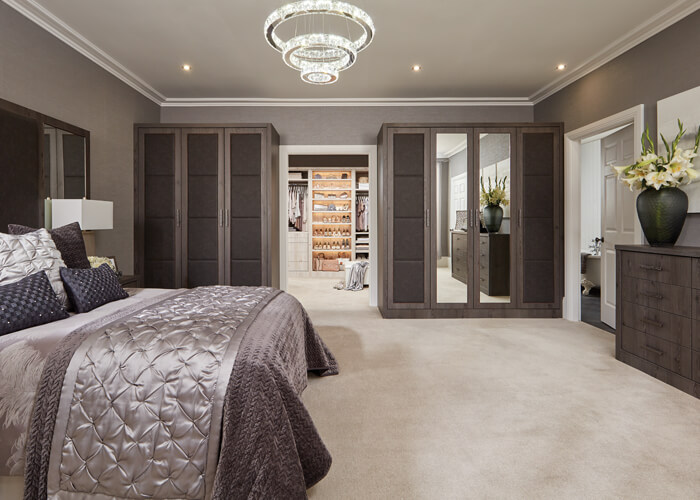 This bedroom features opulent, padded doors and headboards combined with  the warm, contemporary Anthracite Larch finish.