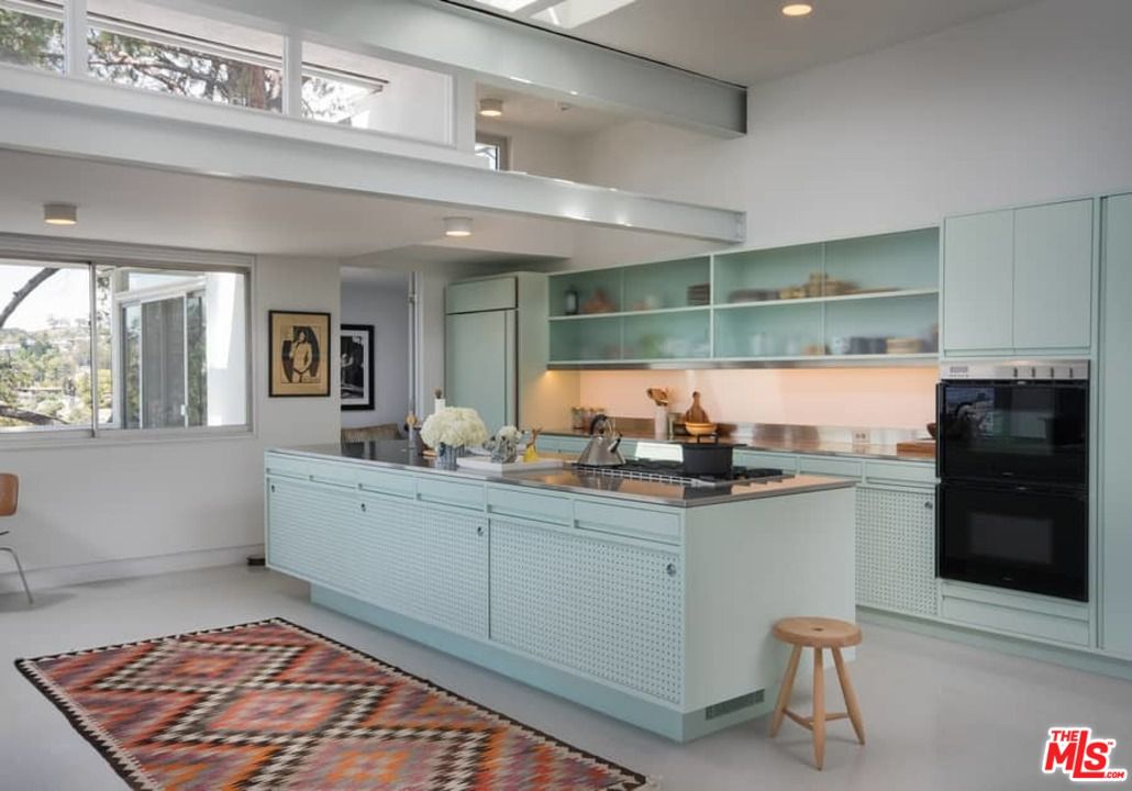 The home features a single wall kitchen with a large center island along  with seafoam-