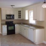 L white wooden kitchen cabinet and mocha granite countertop connected by  black stove and