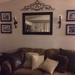 behind couch wall in living room mirror, frame, sconces, and metal
