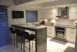 Small modern kitchen with gray quartz counter peninsula and white gloos  cabinets