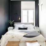 Small Swedish-inspired bedroom with black walls, simple bedding, and  leather stools