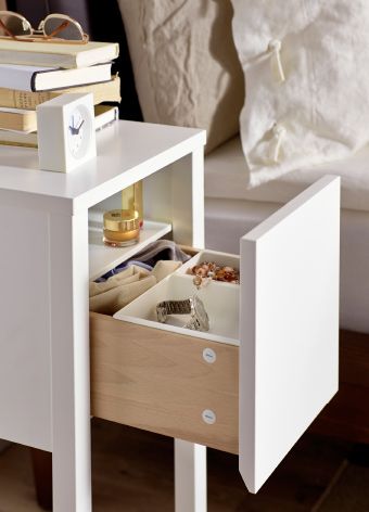 Close-up of small IKEA bedside table, drawer open to reveal inside storage.