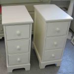 Bedroom. double white wooden Bedside Table having three drawer and white  knob also short.