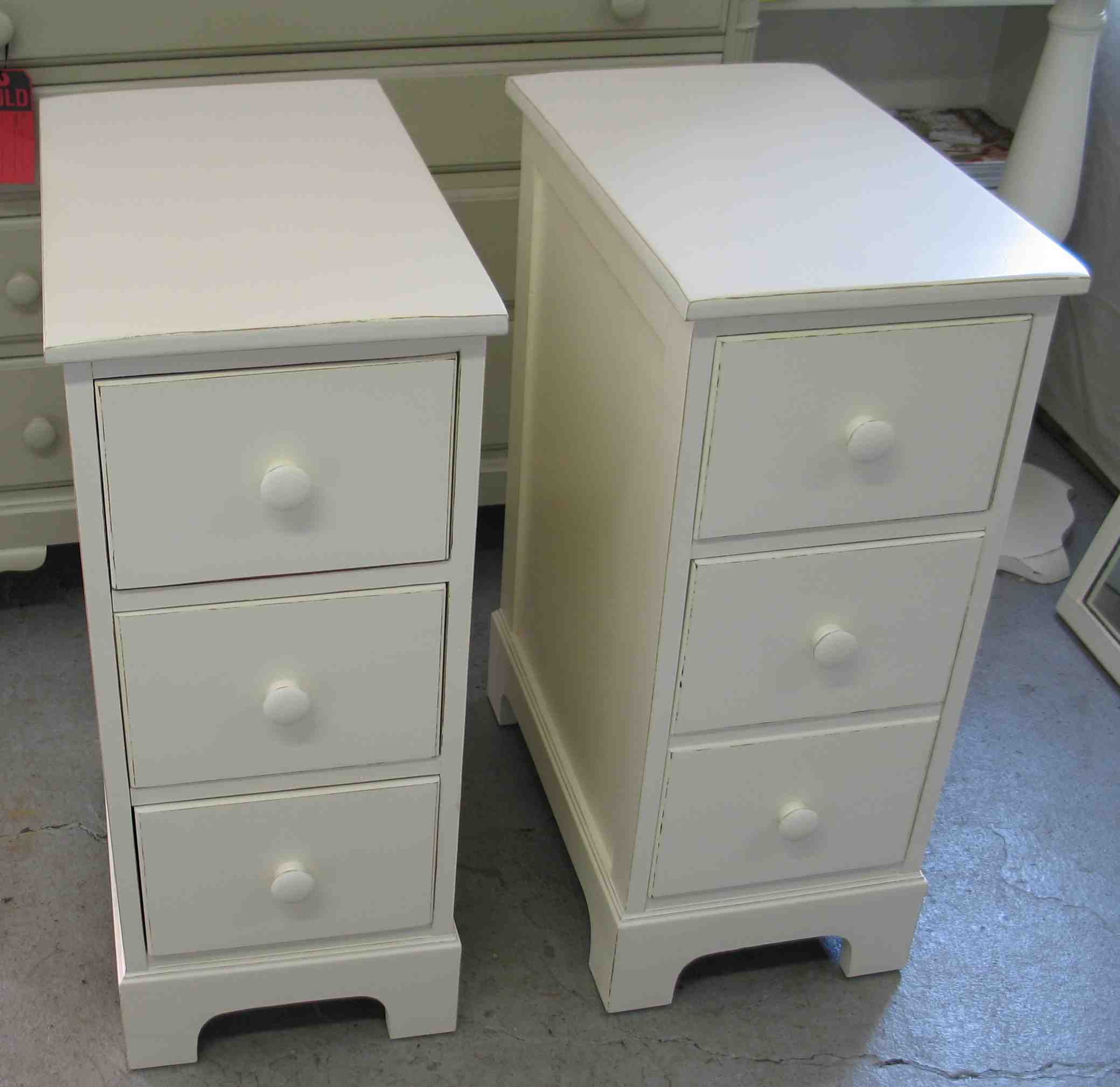 Bedroom. double white wooden Bedside Table having three drawer and white  knob also short.